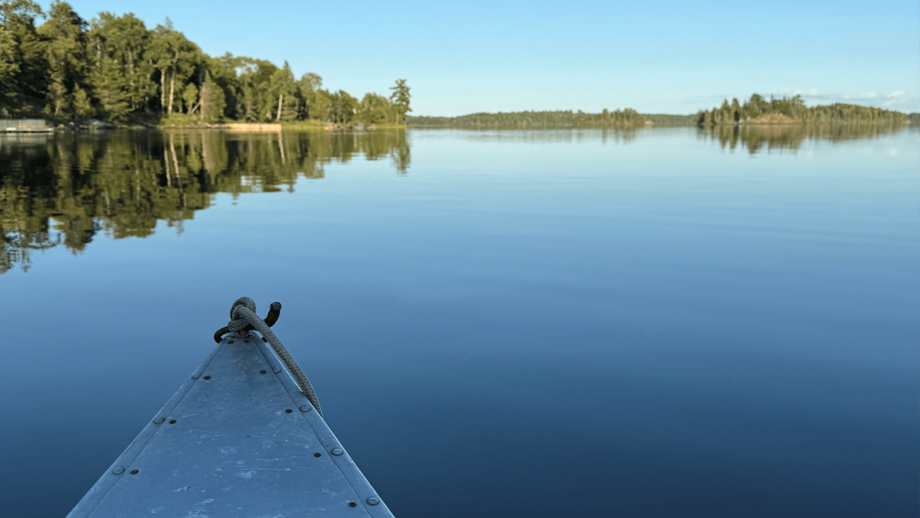 A canoe on a blue lake with forest at the edge