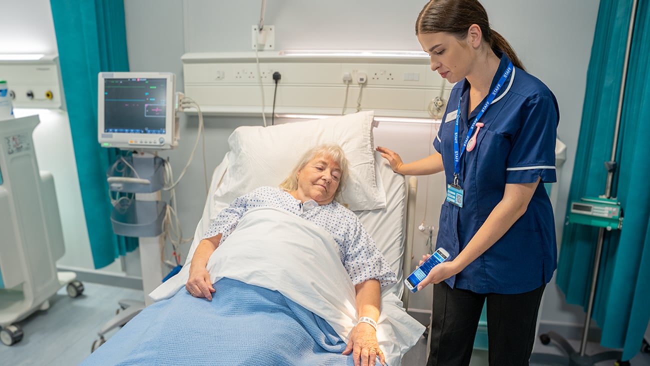 Nurse caring for a patient in hospital bed.