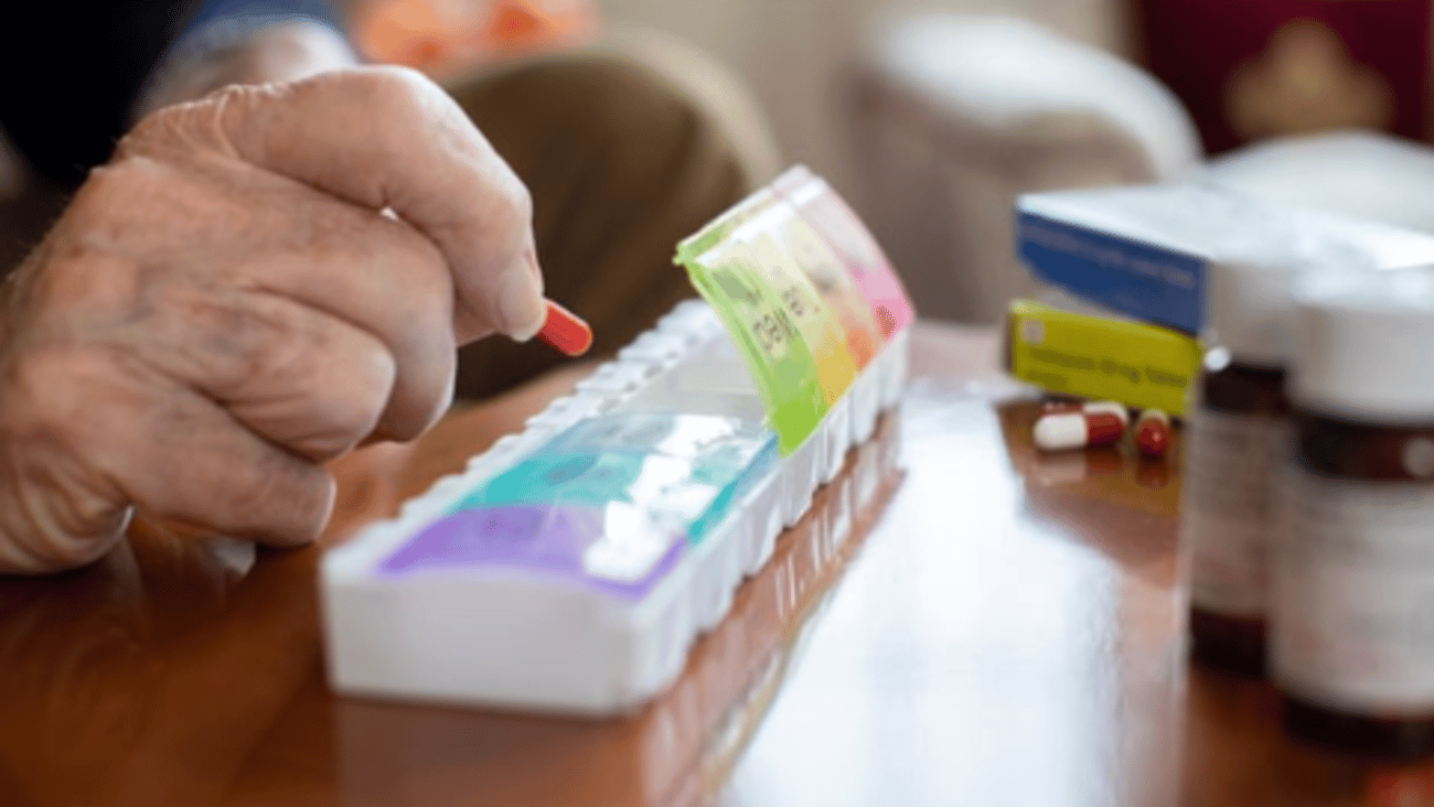 An older person's hands taking pills out of a dosette package