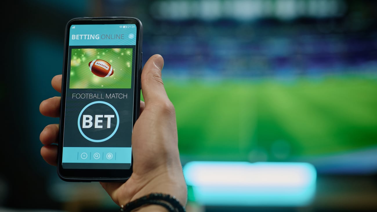 A person holding a phone displaying a sports betting app.