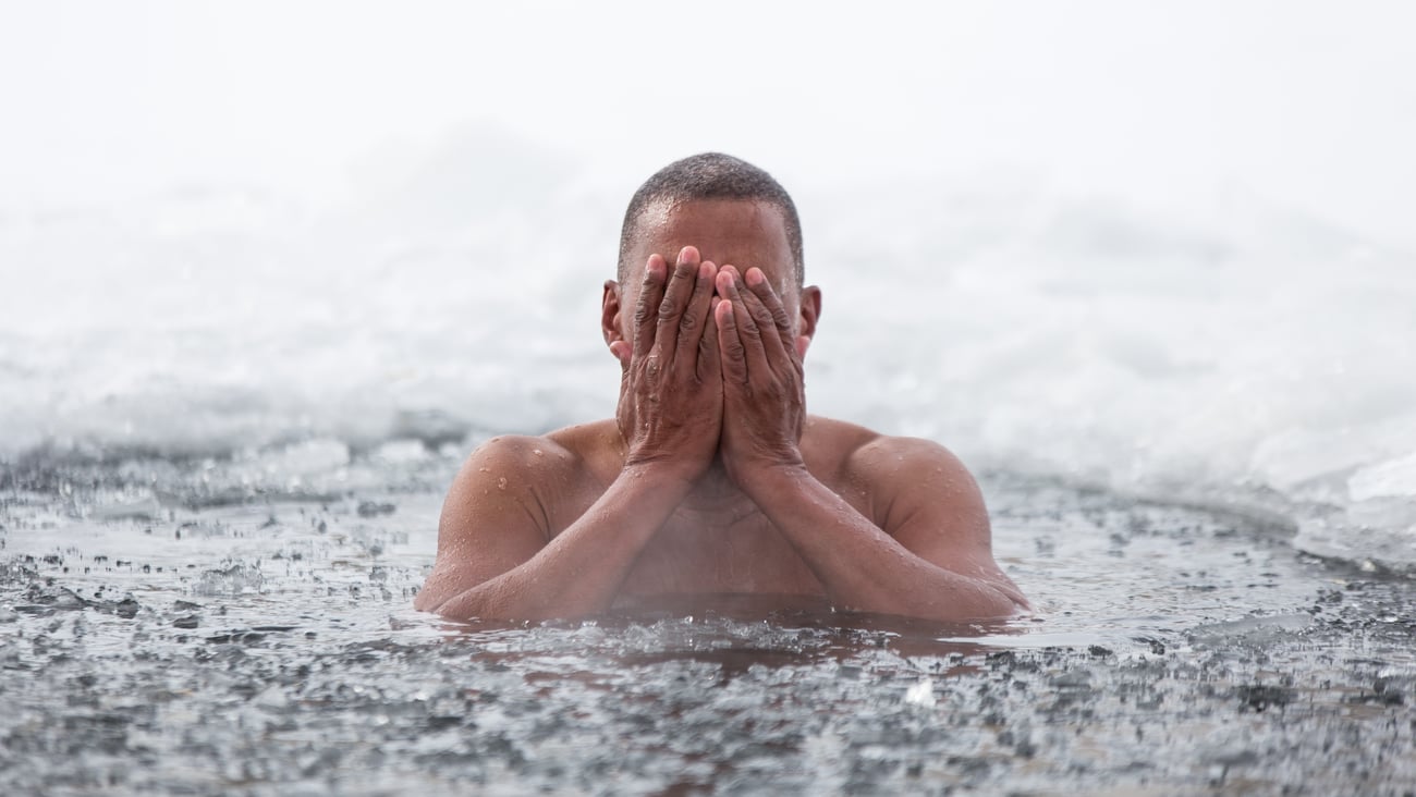 A man swims in an ice hole in the winter.