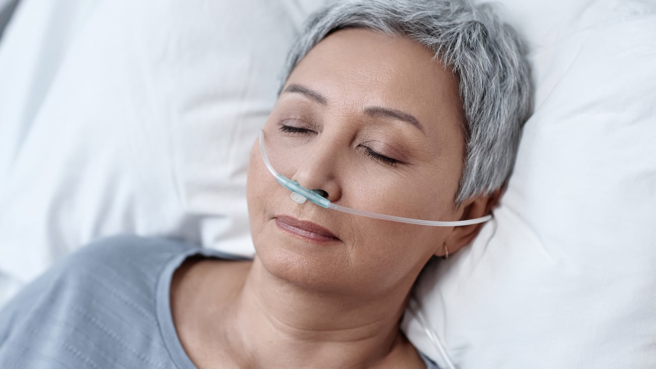woman with short silver hair asleep wearing canula across nose