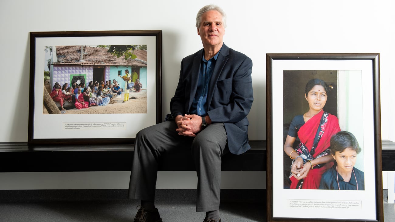 Dr. James Blanchard sitting on a bench with two framed photos of overseas clinics.