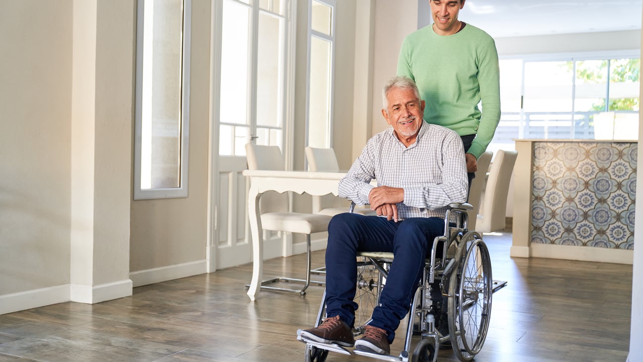 Older man in a wheelchair being looked after by his adult son