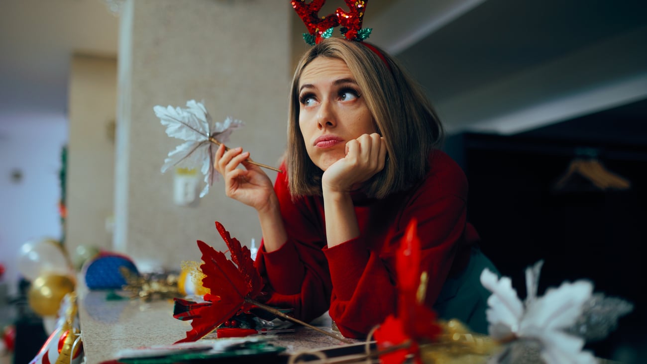 Depressed woman frustrated by the stree of the holidays, wrapping presents wearin bedazzled antlers