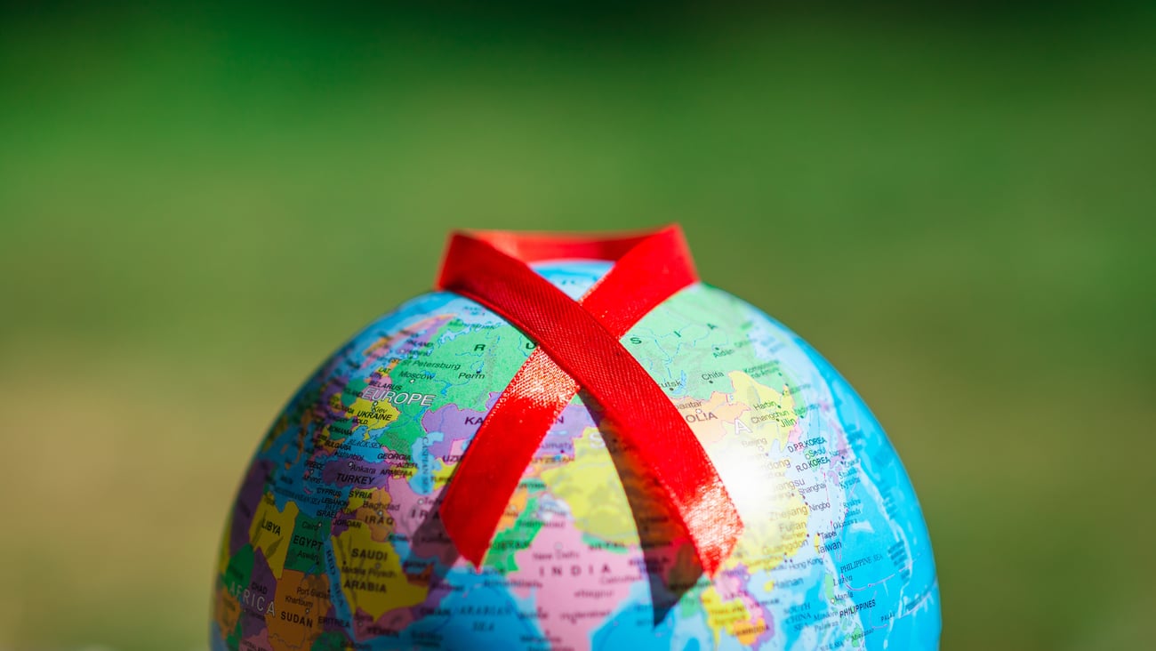 Red AIDs ribbon draped over a globe to represent World Aids Day