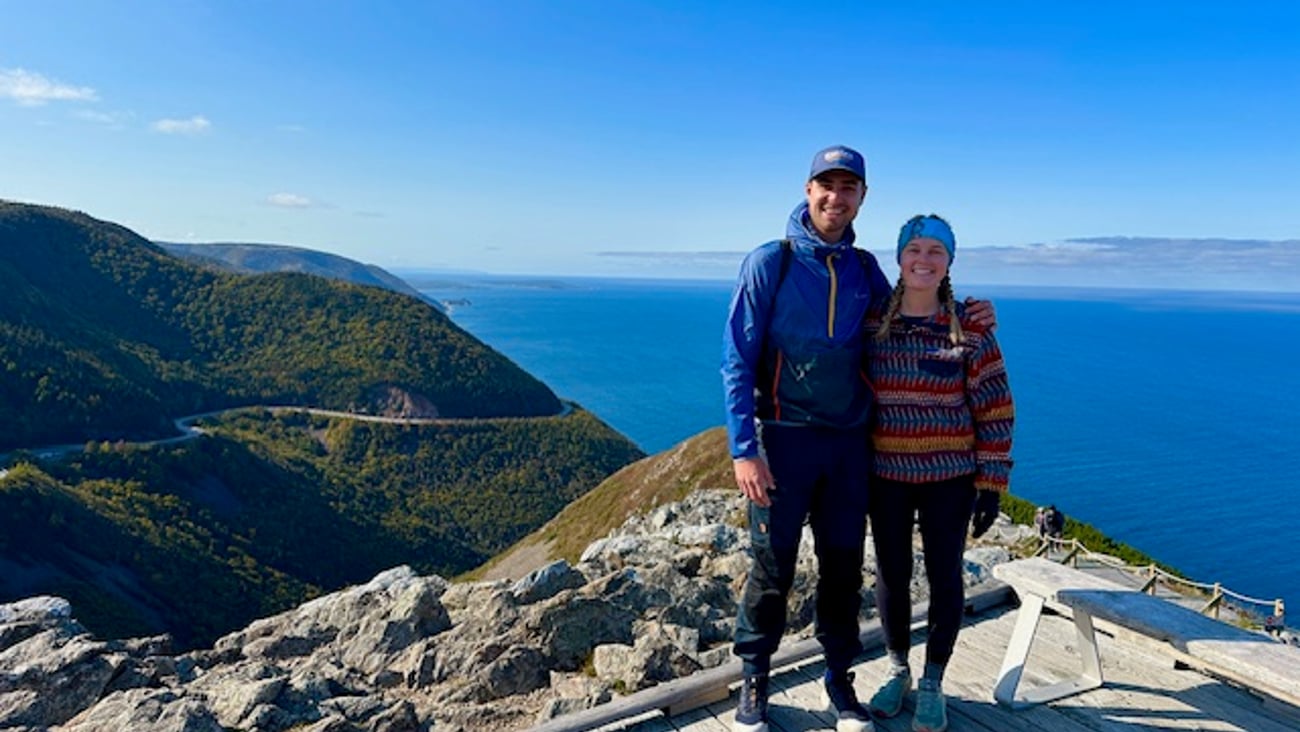 Two adults holding each other for a photo on a picturesque hiking trail