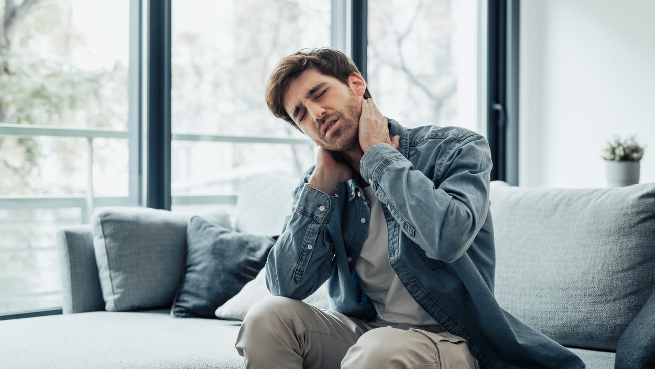 A man adjusts his neck while in pain. 