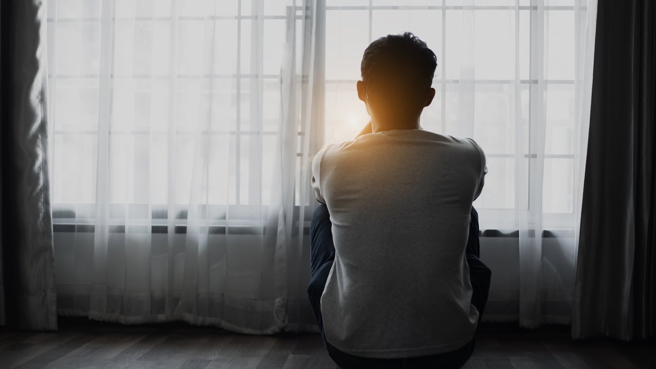 A young man stares out the window in disappointment. 
