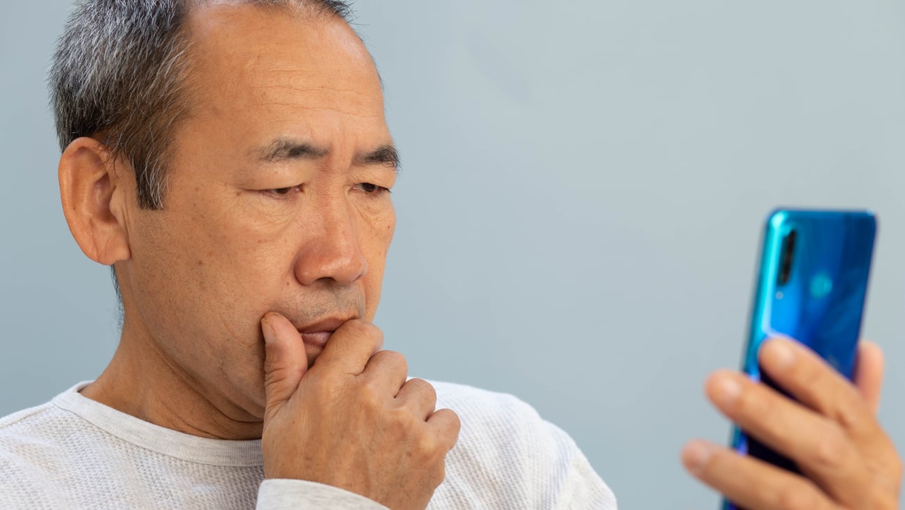 Asian man puzzling over information on screen