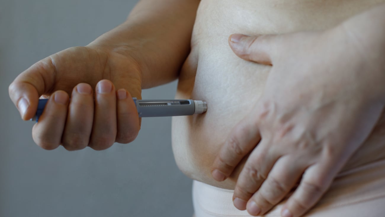 Older fair-skinned person injecting themselves with diabetes medication