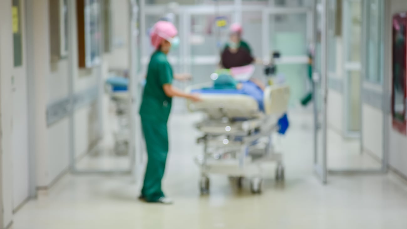 Hospital workers moving a patient on a rolling bed