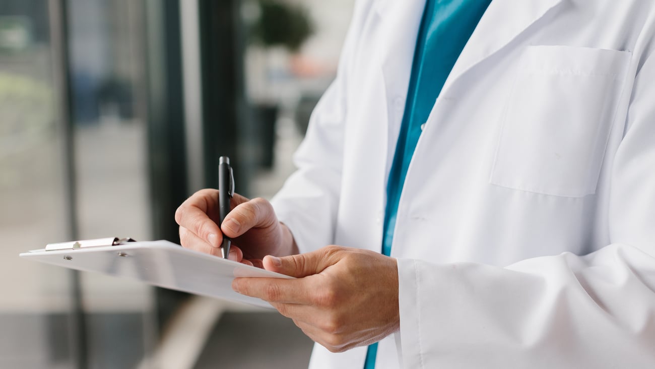 A doctor takes notes on a clipboard.