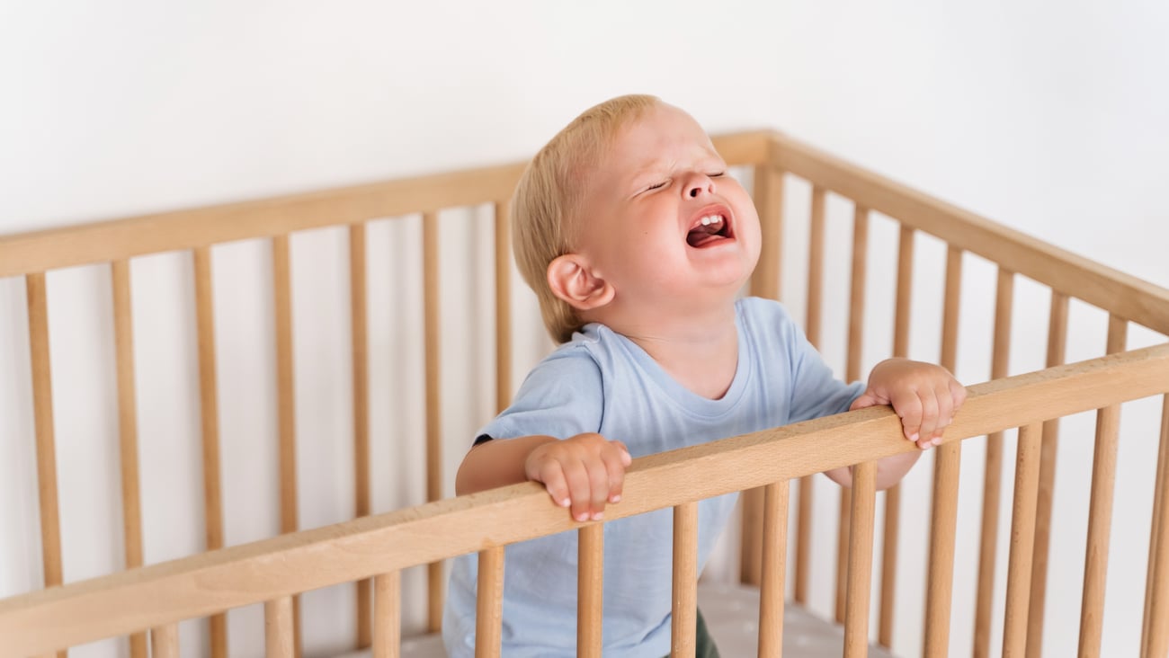 Blonde toddler crying in his crib