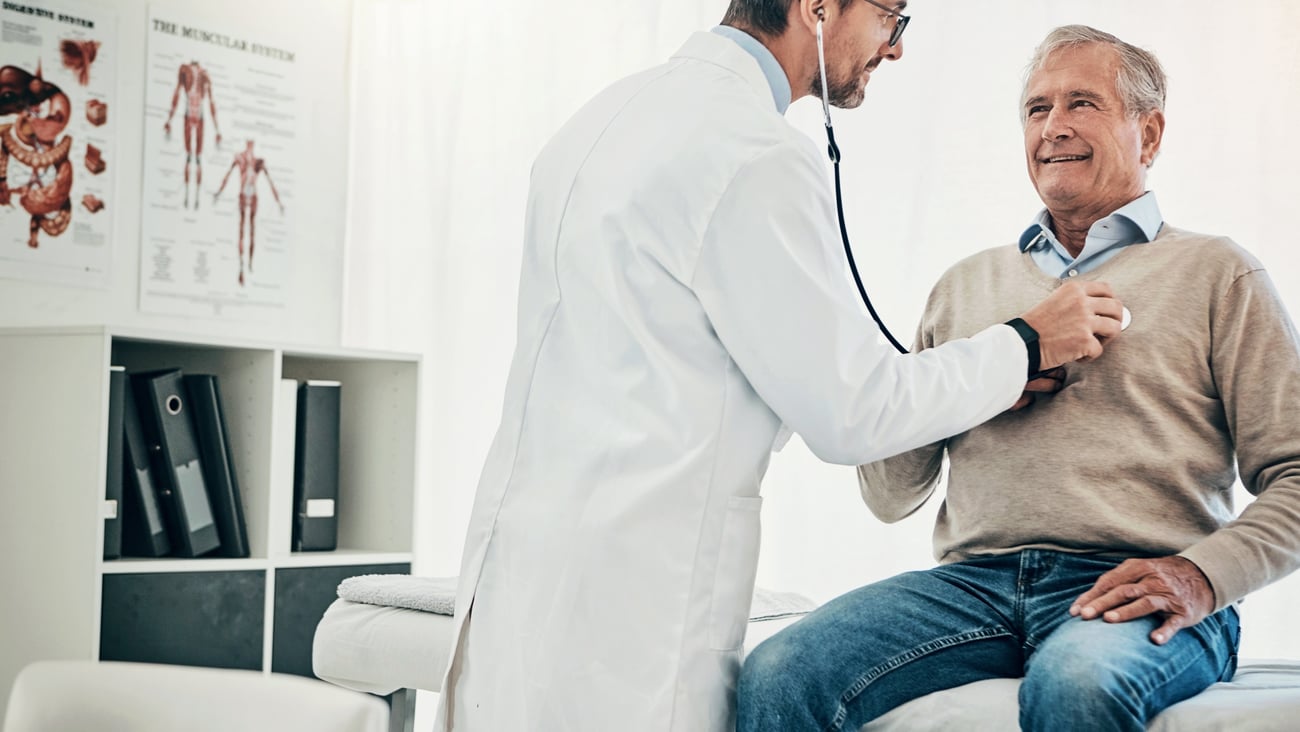 A physician listening to the heartbeat of an older male patient