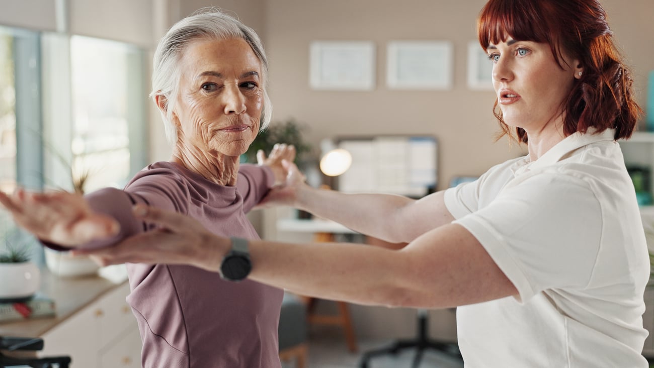 Older woman working on arm stretches with a physiotherapist