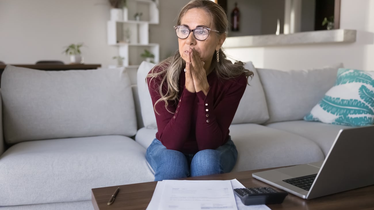 Older woman thinking about the pile of paperwork she has in front of her