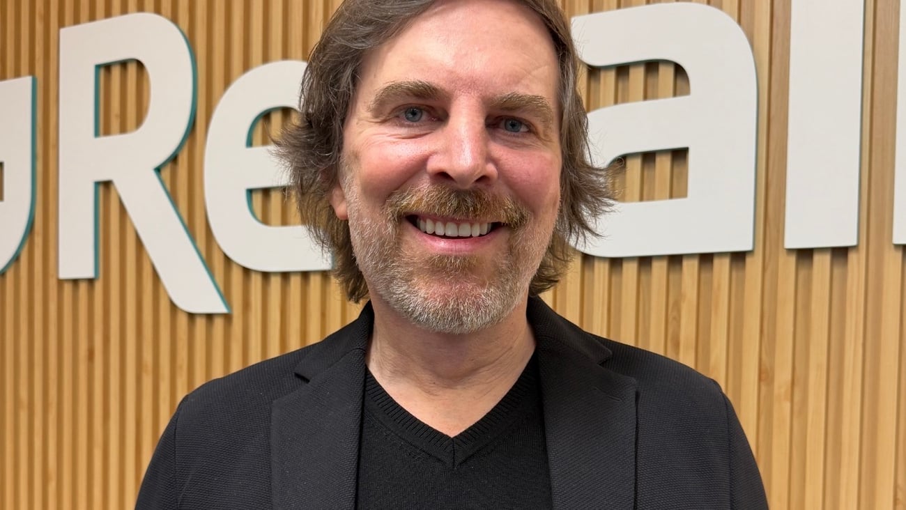 Ron Wilson, Rexall's new CEO, standing in front of a Rexall sign wearing a Black suit 