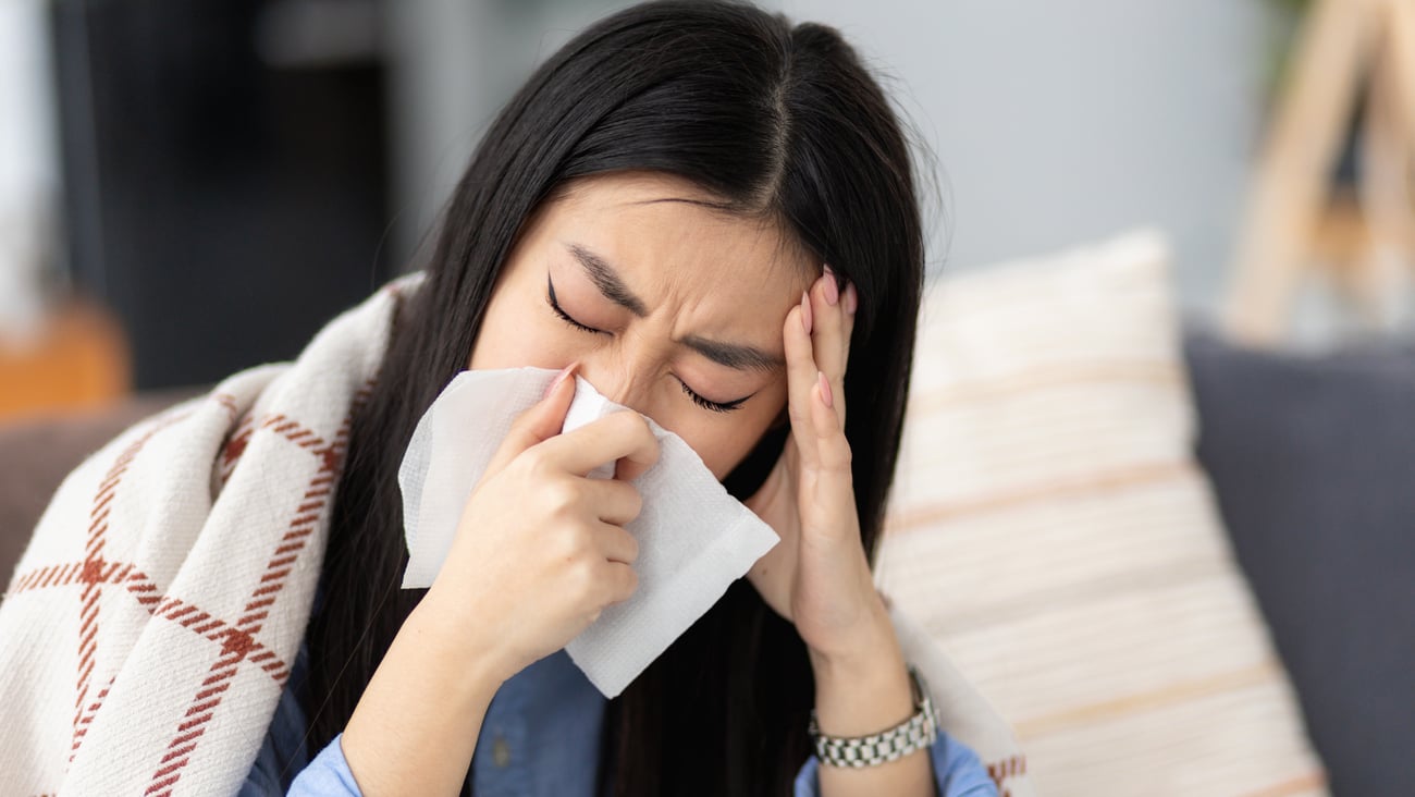 Young Asian woman holding a tissue to her face