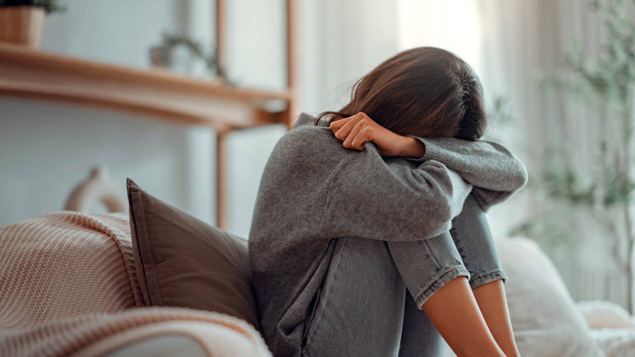 A young woman covering her face while being stressed out.