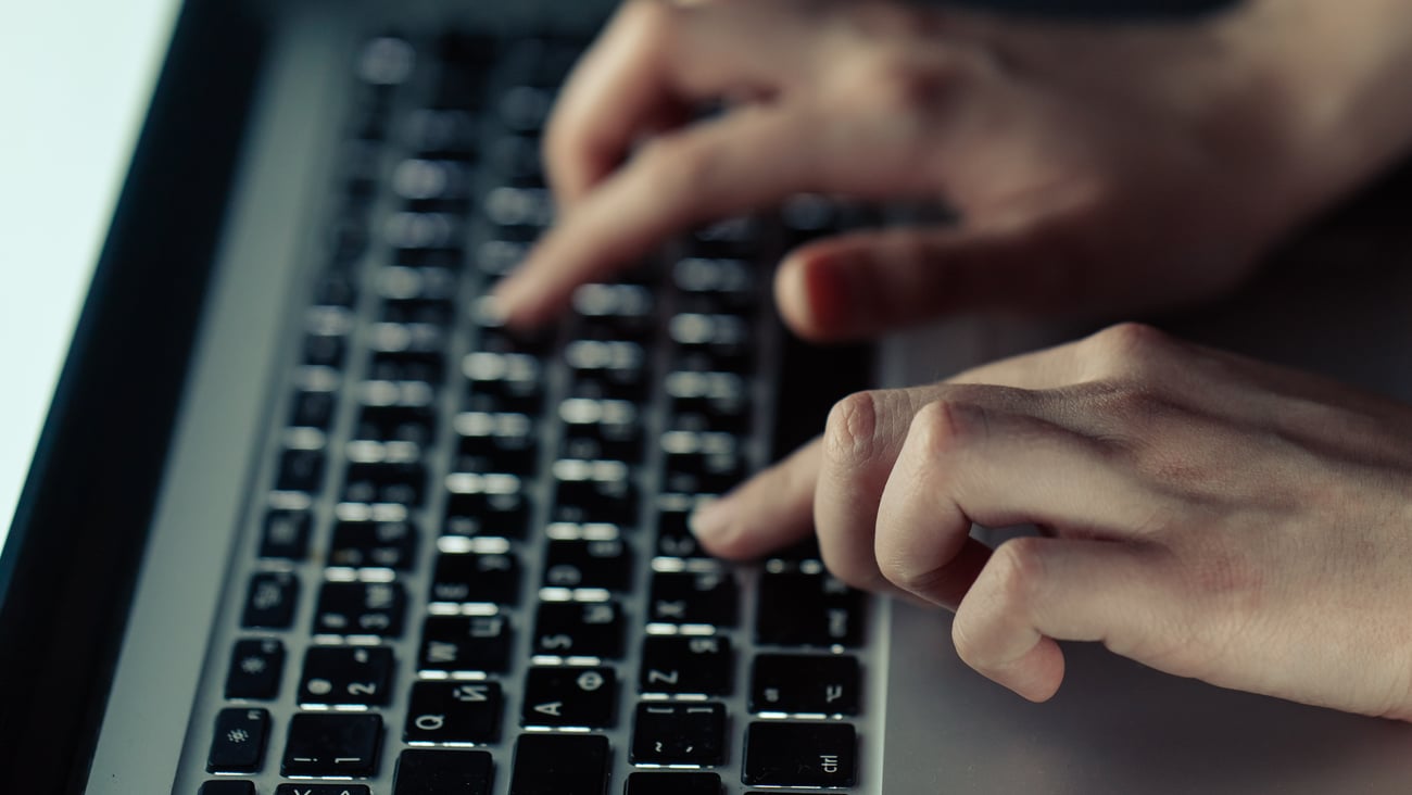 Hands typing on a laptop