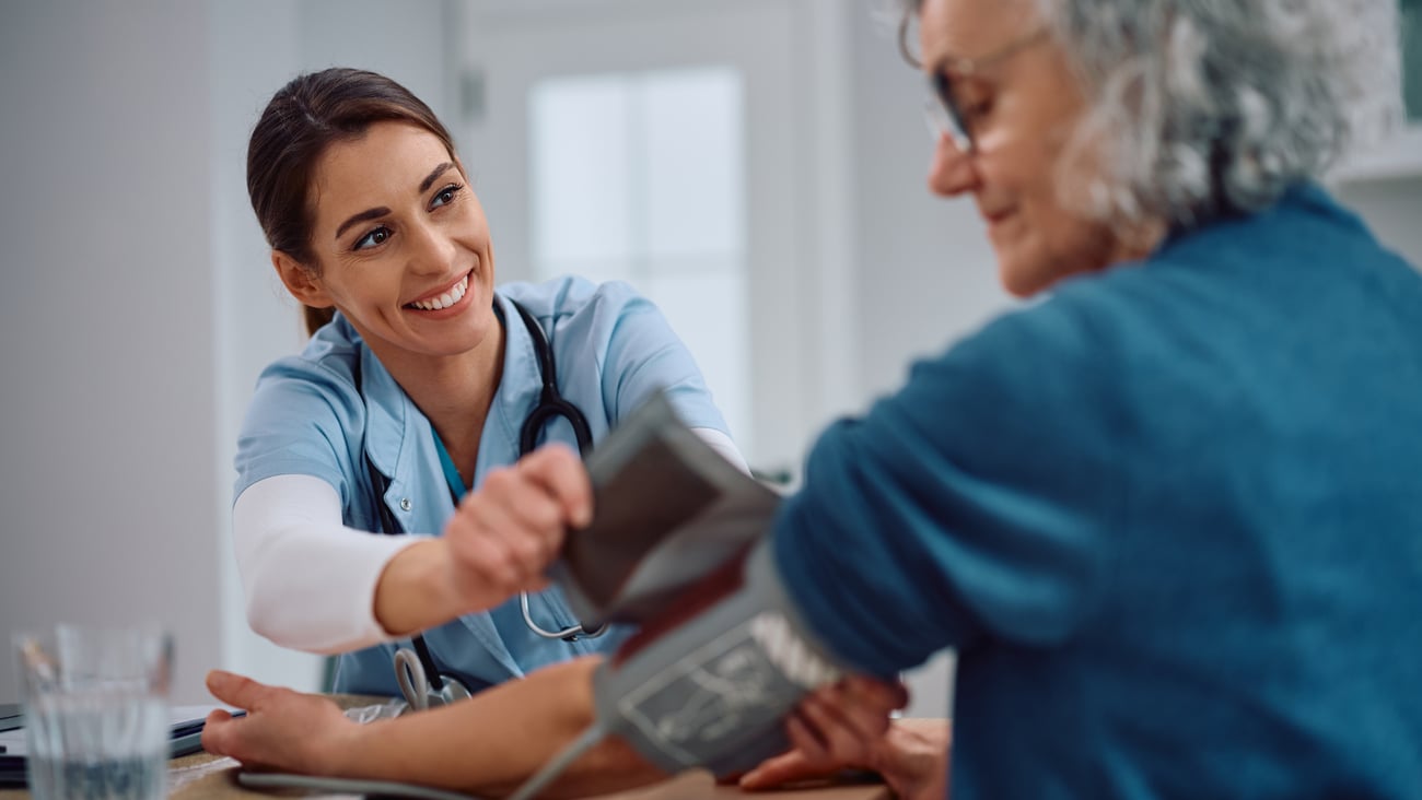 Young woman nurse practitioner putting a blood pressure cuff on an older woman