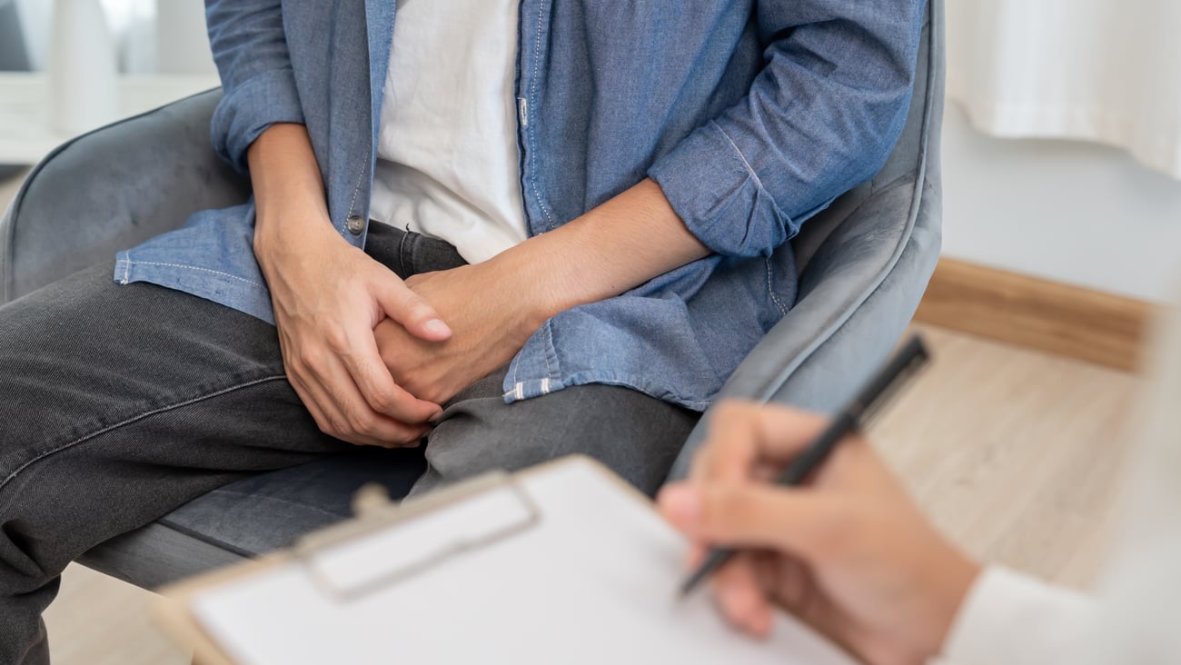 Man hold hand in front of private parts while consulting with a doctor