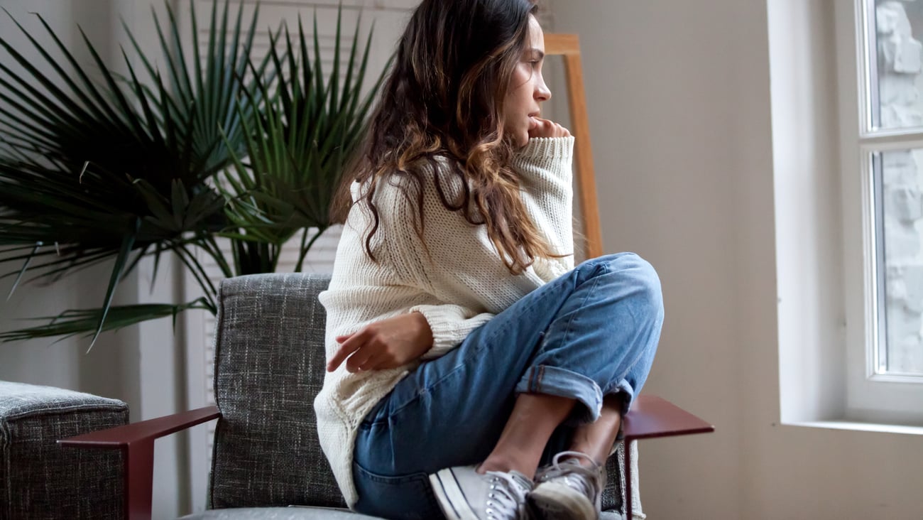 Teen girl sitting.curled up in a chair looking anxious