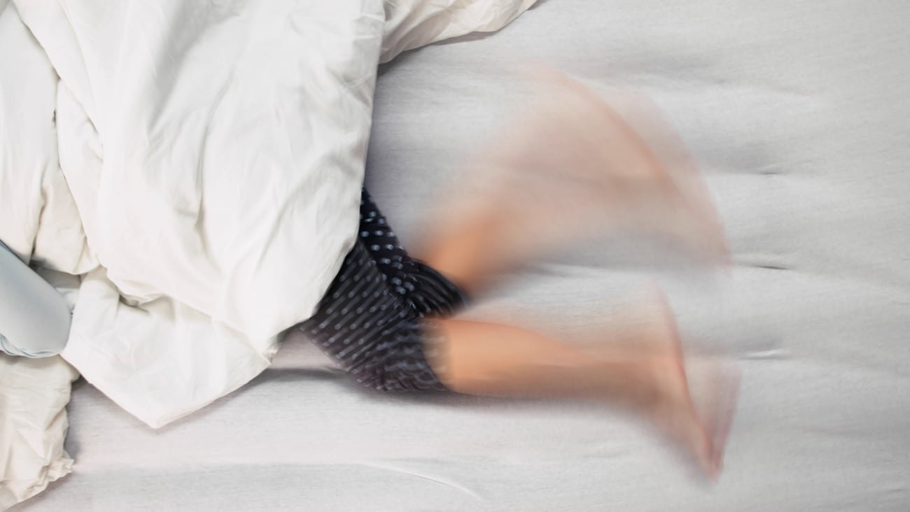 Young woman kicking her legs back and forth in bed