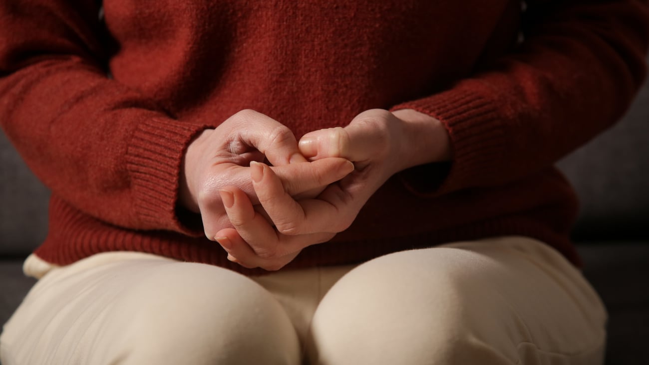 Close up of young adult clenching their hands and picking at the skin on their fingers