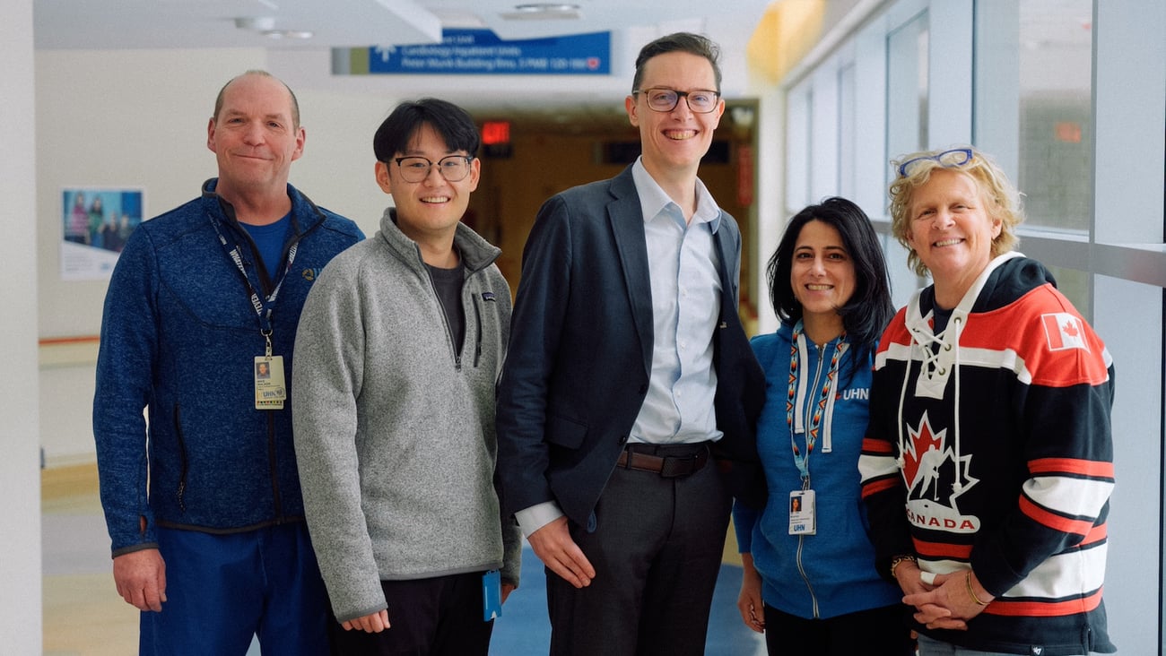 Five researchers stand in a healthcare institution hallway.