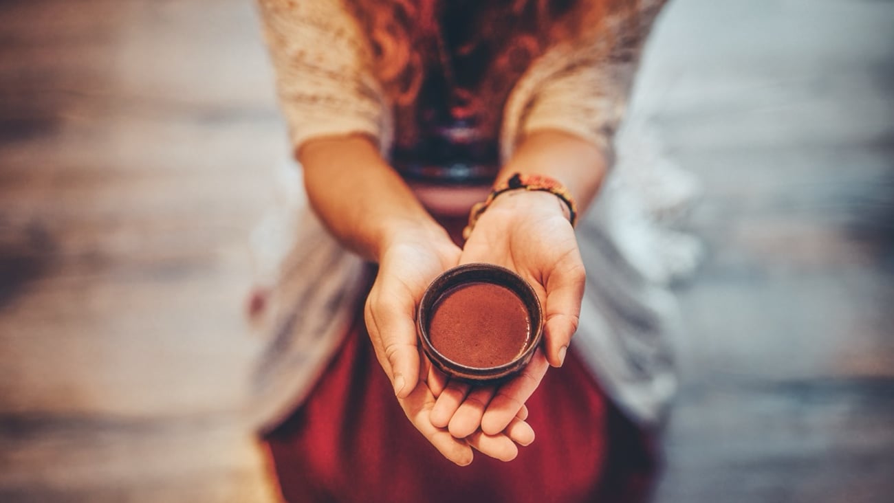 An ayahuasca cup in a woman's hand during a ceremony.
