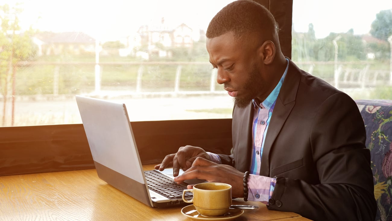 A black man wearing a suit at a laptop computer