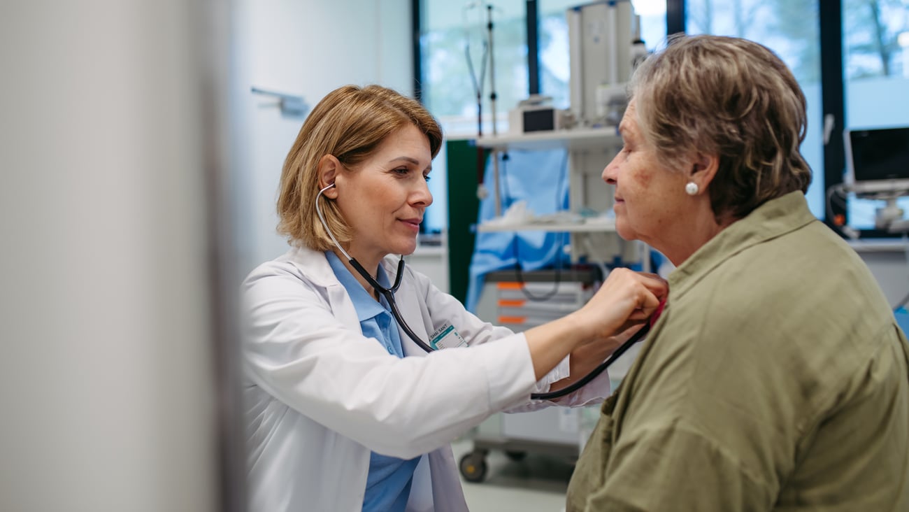 Woman doctor listening to the heartbeat of an older woman patient