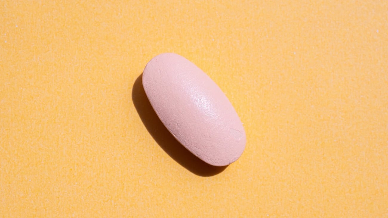 Pink medicine pill tablet on orange background
