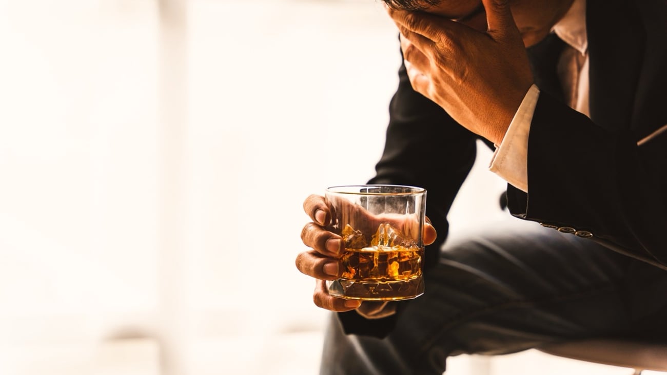 A man in a suit holding an alcoholic drink.