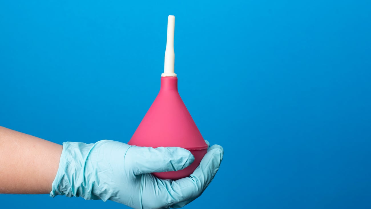 Enema in the hand of a nurse on a blue background
