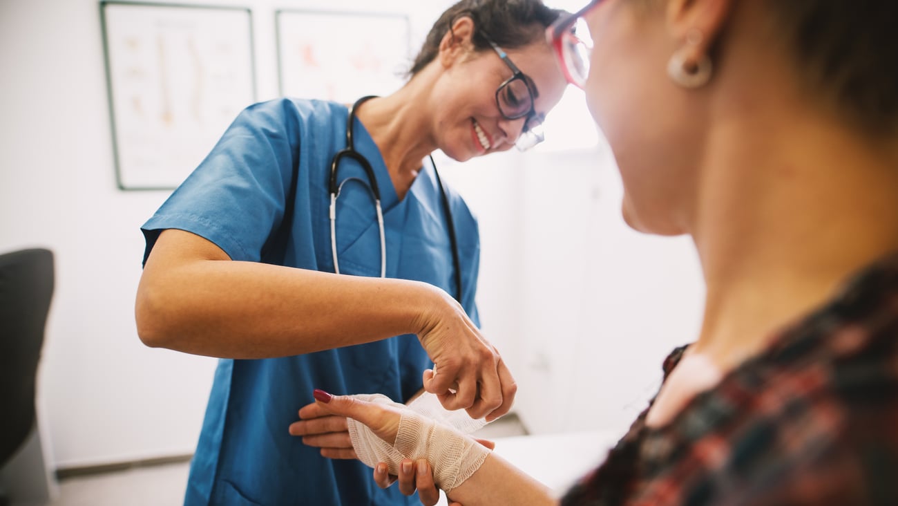 Nurse wrapping a patient's wrist and hand in gauze