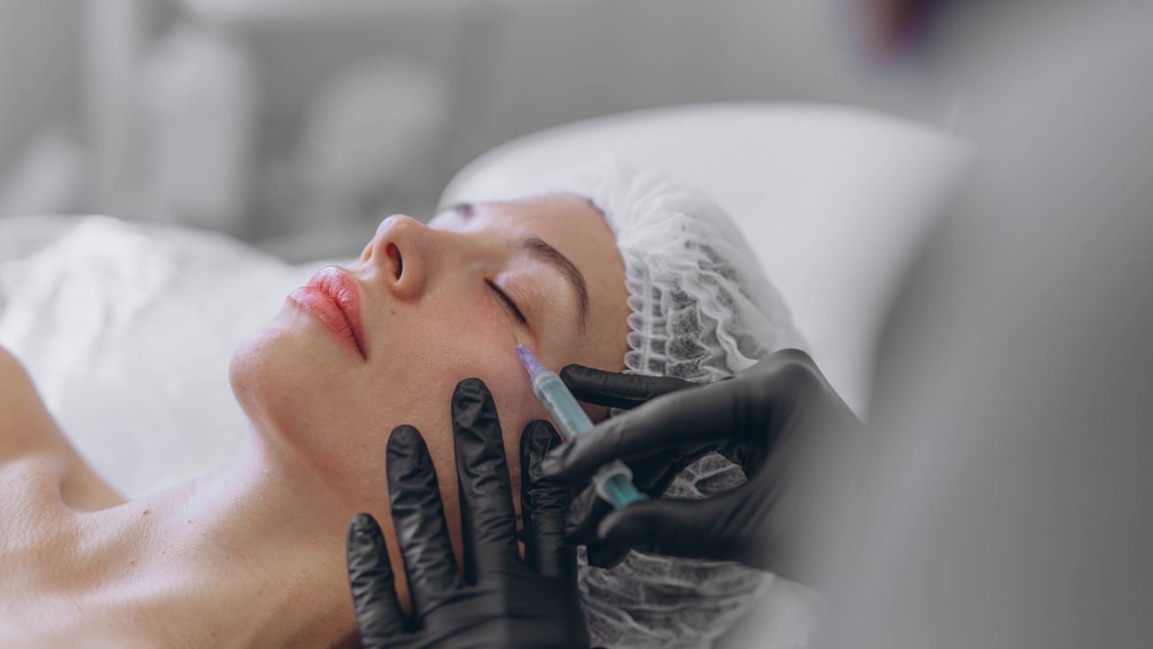 A professional beautician injects into the face of a young woman