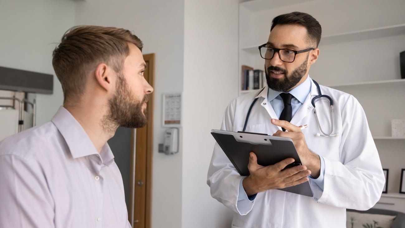 A male doctor sees a patient in his office.