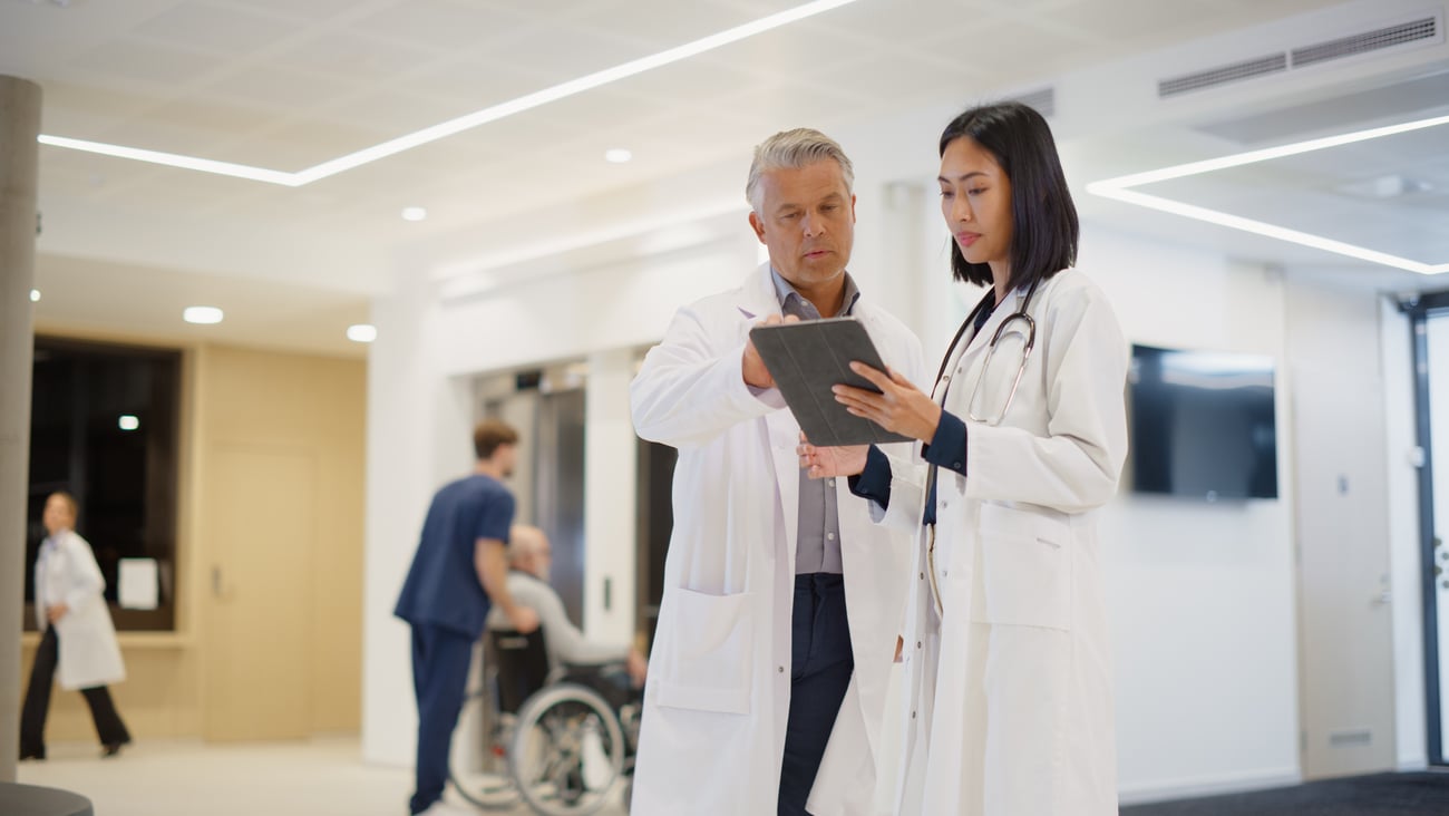 Two doctors chatting, reading notes on a tablet