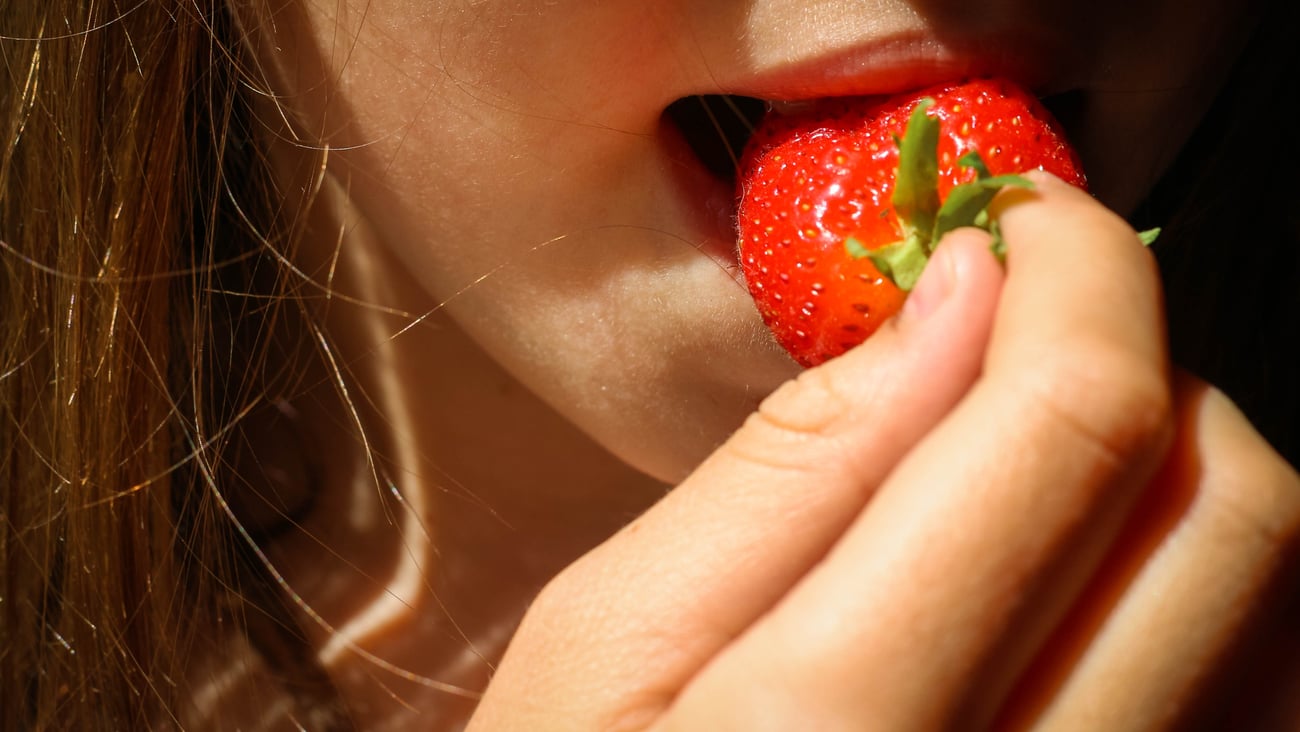 Close up of a fair-skinned young woman eating a strawberry