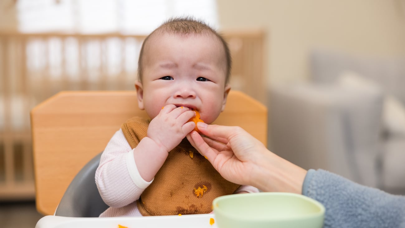 An baby sloppily eating in a high chair
