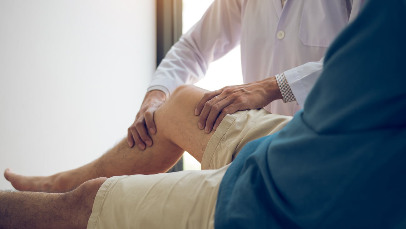 A physiotherapist helping a patient bend their knee 