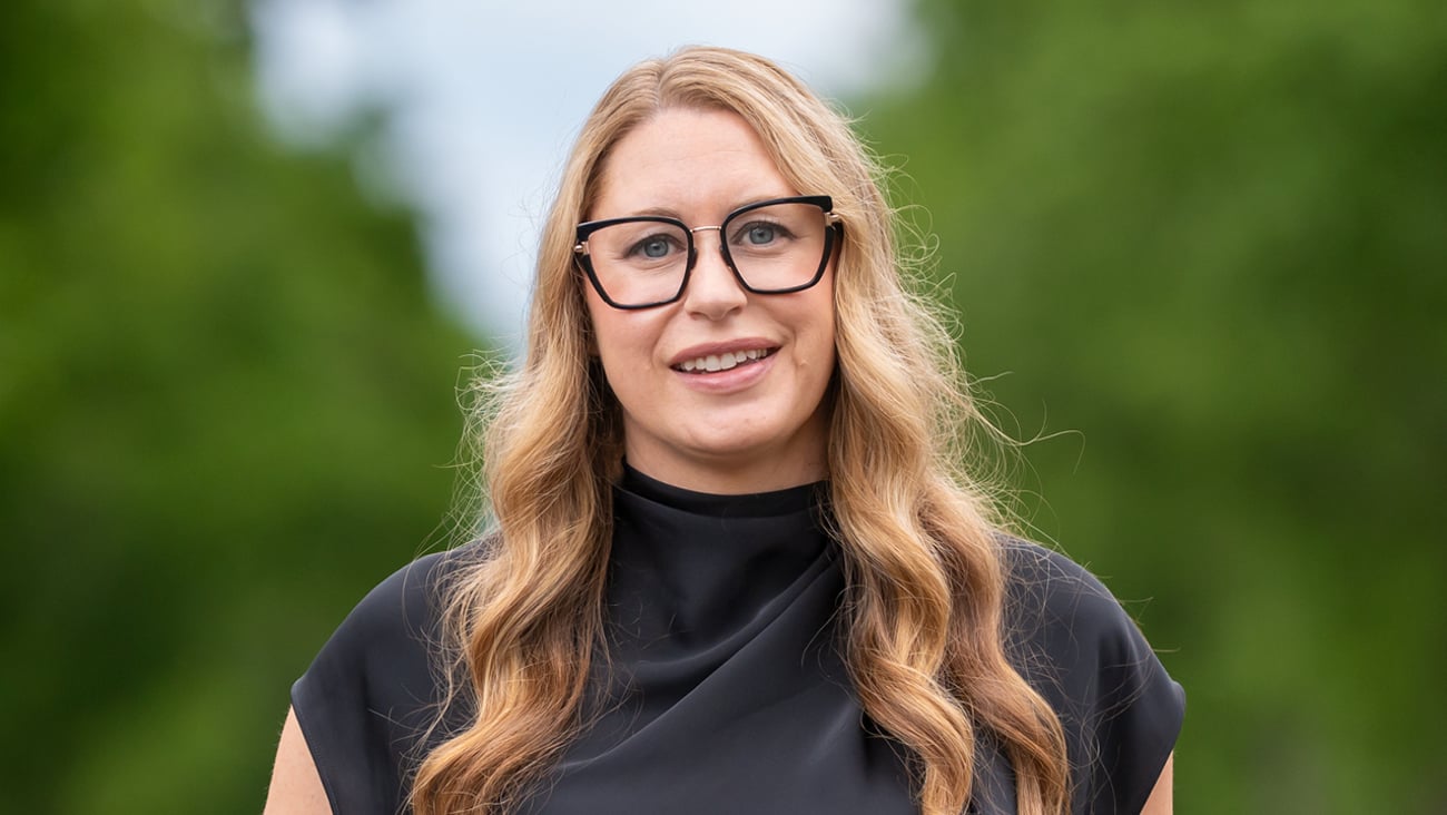 A blonde woman with glasses standing outside