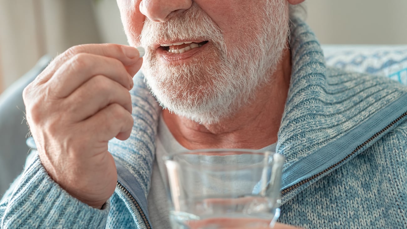 Older fair-skinned man taking a pill
