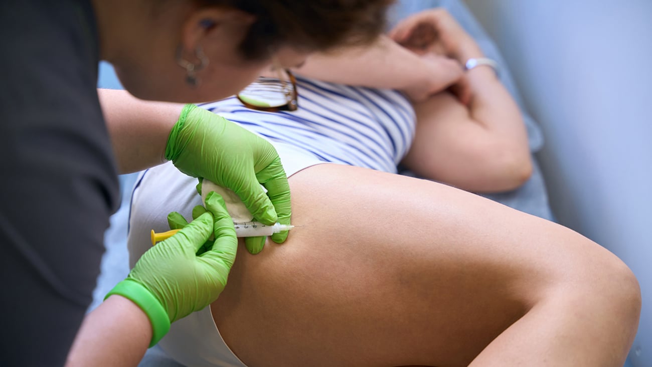 Nurse injecting medicine into a patient's upper thigh