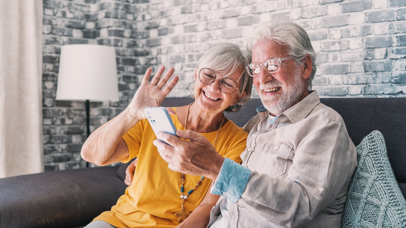 An older white couple video chatting with someone on a smartphone
