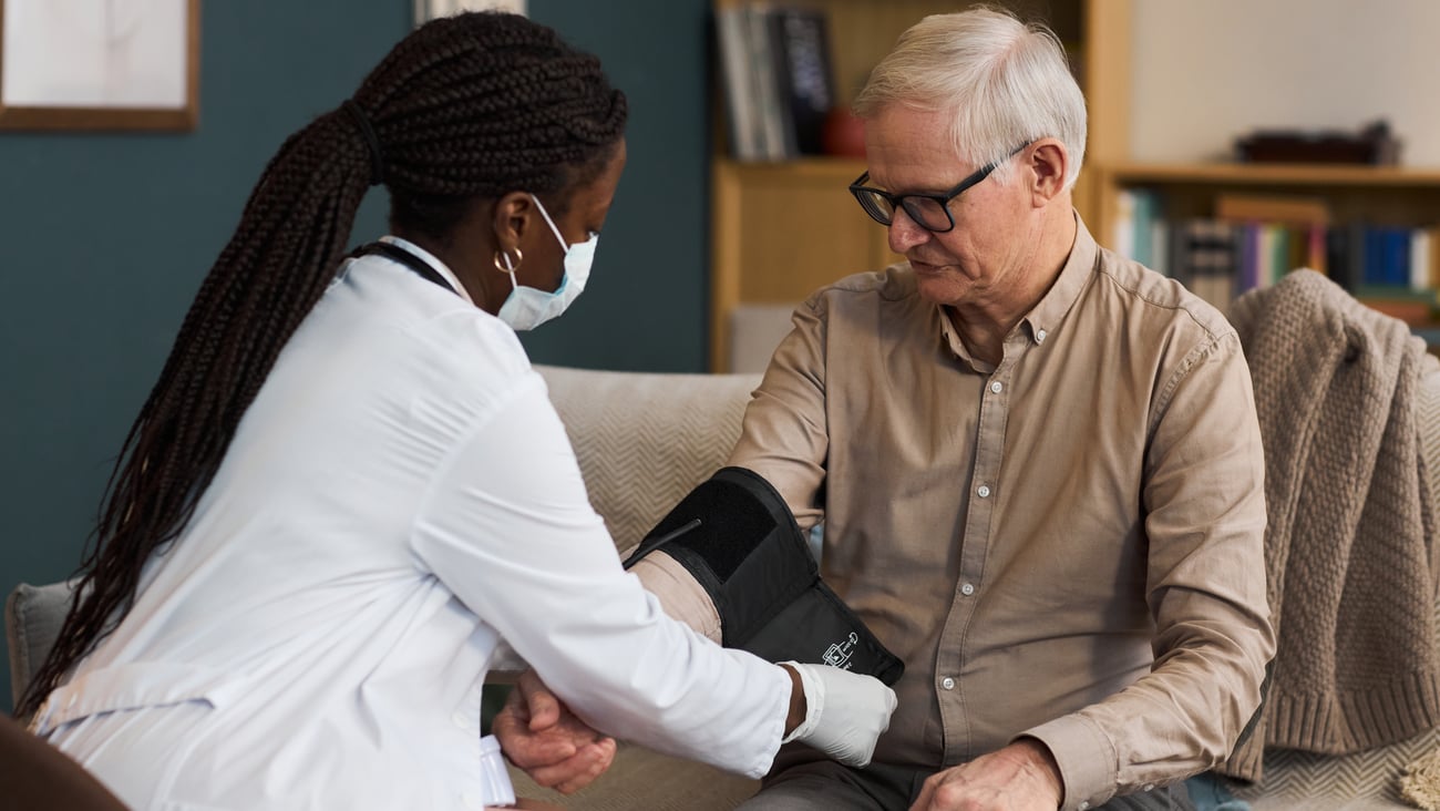 A doctor putting a blood pressure cuff on an older man