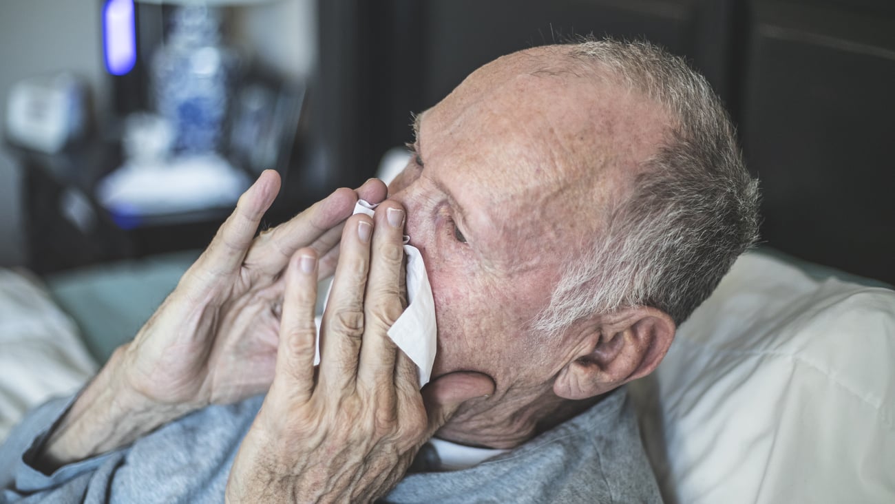 elderly man blowing his nose